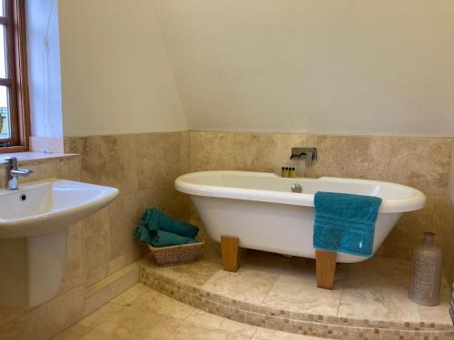 2 Beds & living in our idyllic country Cottage في بيدفورد: حمام مع حوض استحمام ومغسلة