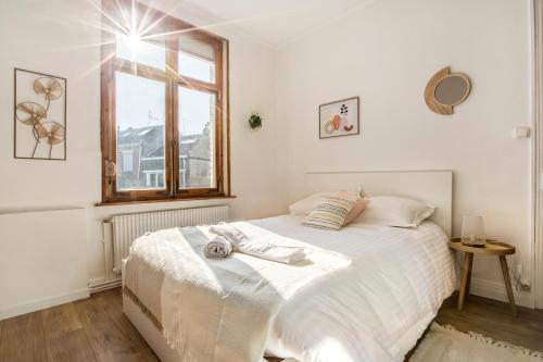 una camera da letto con un grande letto bianco con una finestra di Le Cottage de l'Hippodrome. a Lambersart