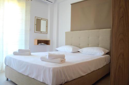 a bedroom with a white bed with towels on it at Α & D Perikleous Apartments in Kyllini