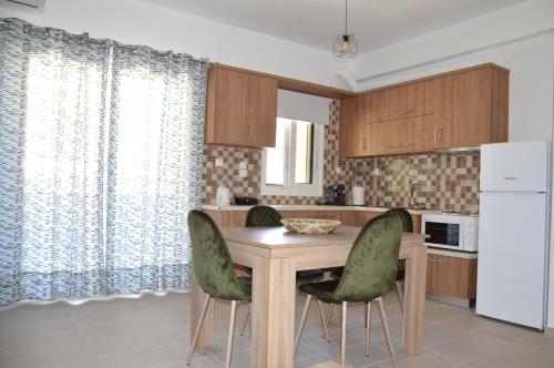 a kitchen with a wooden table and green chairs at Α & D Perikleous Apartments in Kyllini
