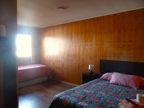 a bedroom with a bed and a wooden wall at Hostal Santa Fe in Castro