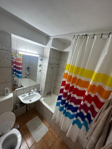 a bathroom with a rainbow shower curtain and a sink at Apartament Calea Grivitei Podul Grand in Bucharest