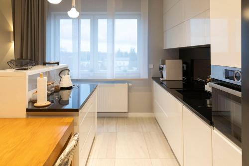 eine Küche mit weißen Schränken und einer Glasscheibe in der Unterkunft Apartament Termalny DELUX in Uniejów