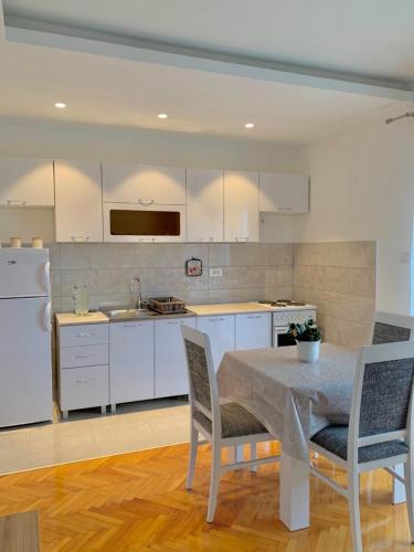 a kitchen with white cabinets and a table and chairs at Talija Apartments in Bijela