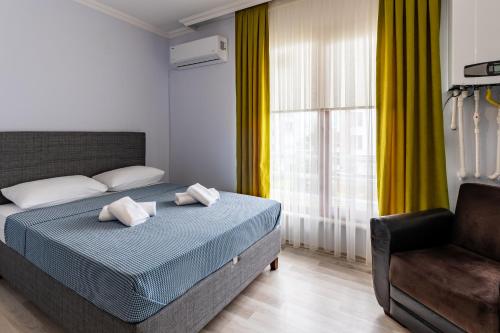 a bedroom with a bed and a chair and a window at Flora Trabzon Apart in Pelitli
