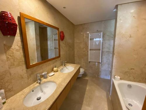 a bathroom with two sinks and a mirror and a tub at Golf resort villa in Bouskoura