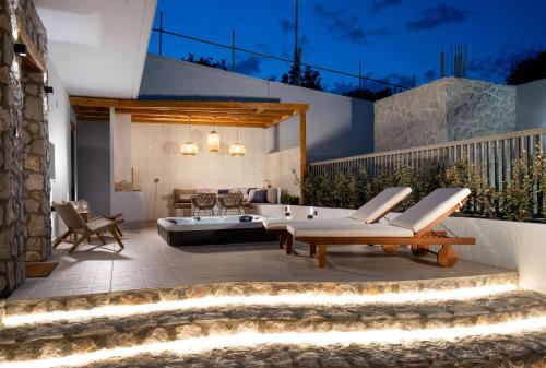 a patio with a tub and chairs and a table at Lithos Luxury Villa in Archangelos