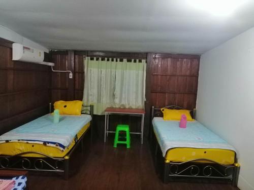 a room with two beds and a table and a chair at Lungmin homestay in Mae Hong Son