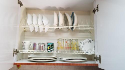 eine Speisekammer mit Tellern und Geschirr auf einem Regal in der Unterkunft Lindo apto al lado del parque del ingenio in Cali