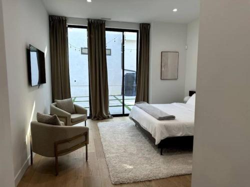een slaapkamer met een bed, een stoel en een raam bij New High-End Luxury Pet-Friendly Villa in Los Angeles