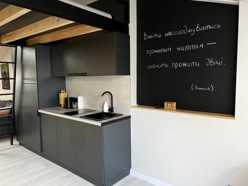 a kitchen with black cabinets and a sink at «ГОРИ́ЩЕ на площі Польський ринок» in Kamianets-Podilskyi