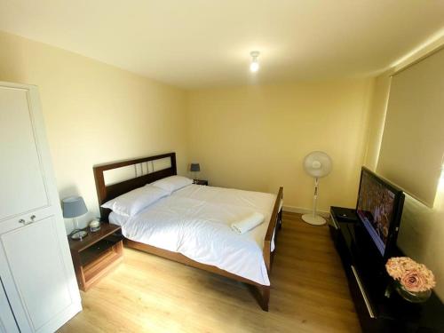 a bedroom with a large white bed and a flat screen tv at Private Gated Studio Flat in Buckinghamshire