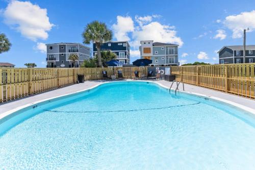 a large swimming pool with a wooden fence at The Beach House at Oak Island by North State Hospitality in Oak Island