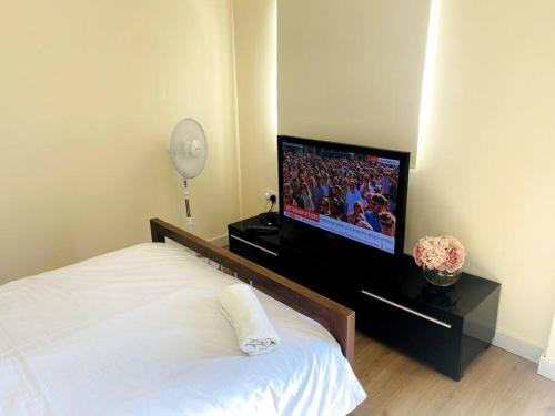 1 dormitorio con 1 cama y TV de pantalla plana en Private Gated Studio Flat, en Buckinghamshire