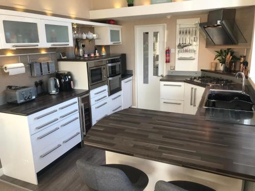 a kitchen with white cabinets and a wooden counter top at Hot Tub Accommodation North Wales Lodge in Rhyl