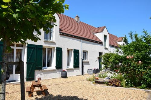 een wit huis met groene luiken en een tuin bij ô temps de l'escapade in Saint-Père-sur-Loire