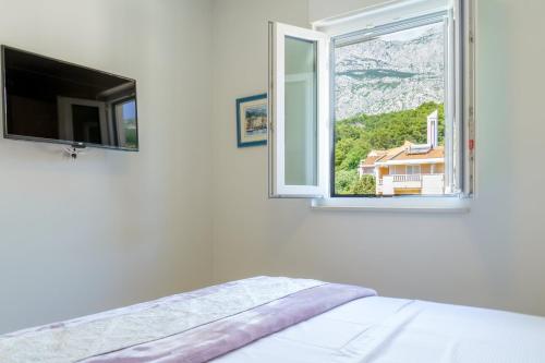 a bedroom with a tv and a bed and a window at Emilia Lofts in Tučepi