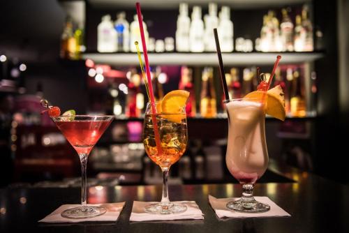 three cocktails sitting on top of a bar at Grandhotel Ambassador Národní Dům in Karlovy Vary