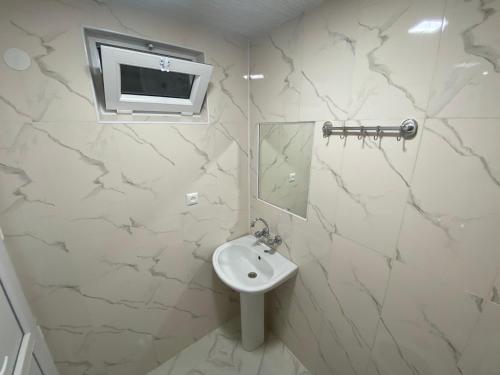 a white bathroom with a sink and a mirror at Guesthouse LUKA in Kutaisi