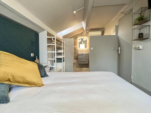 a bedroom with a large white bed with a yellow pillow at Hotel La Calanque in Mandelieu-la-Napoule