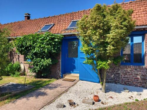 une porte bleue sur une maison en briques avec un arbre dans l'établissement Studio à 15 minutes des falaises et proche des étangs, à Dargnies