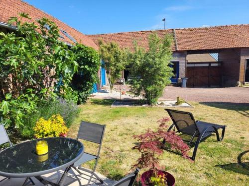 un patio avec une table et des chaises dans une cour dans l'établissement Studio à 15 minutes des falaises et proche des étangs, à Dargnies