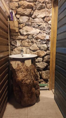 a stone bathroom with a sink in front of a stone wall at Na krovu svijeta in Lukomir