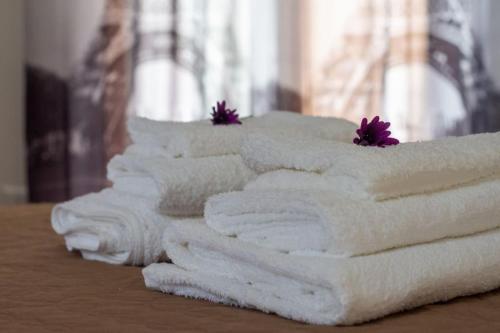 una fila di asciugamani bianchi su un tavolo con fiori viola di Aela Home a Pisa