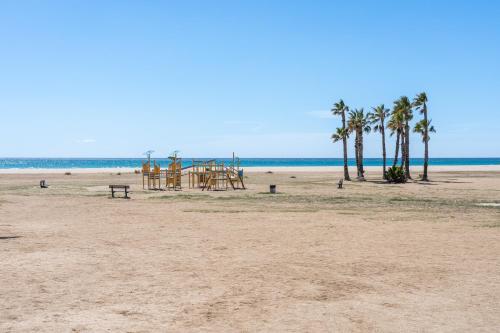 a sandy beach with palm trees and a playground at 1ª LÍNEA DE PLAYA. Apartamento: LA CALMA in Comarruga