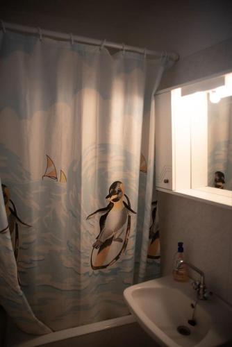 a bathroom with a penguin shower curtain next to a sink at Michalis little sunrise in Mamádhos
