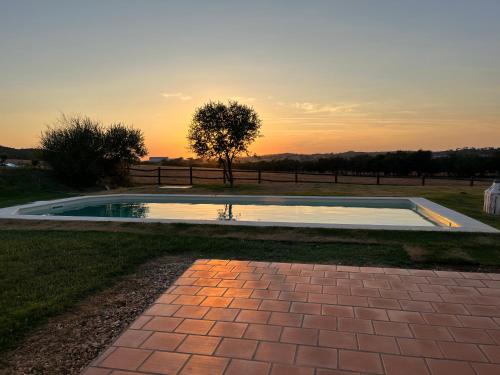 a pool in the grass with a sunset in the background at Casa Bendi in Cuba