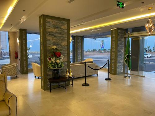 a lobby with a couch and a vase of flowers on a table at فندق حياة تاون 2 in Umm Lujj