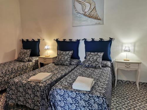 two beds in a room with two tables and two lamps at Roda' in Panarea