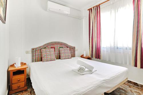 a bedroom with a white bed with a laptop on it at Espanhouse Alina in Orihuela Costa