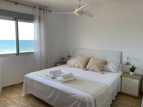 a white bedroom with a large bed with towels on it at Cara al mar in Cullera