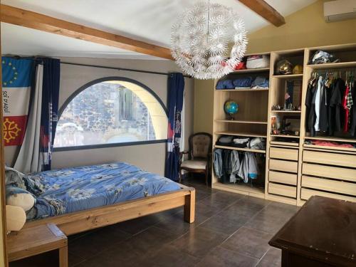 une chambre avec un lit et une grande fenêtre dans l'établissement Maison de village avec patio, à Bessan