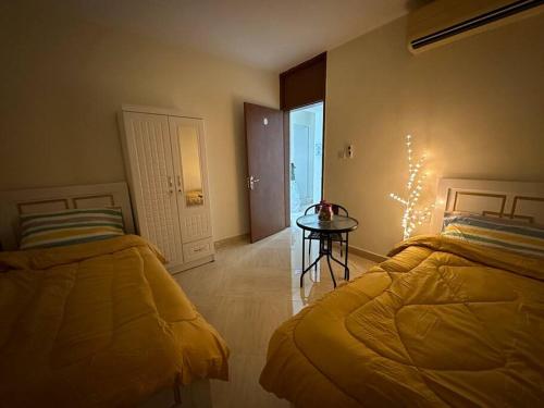 a bedroom with two beds and a table and a door at Private Room Shared Apartment Flat31-R1 in Abu Dhabi