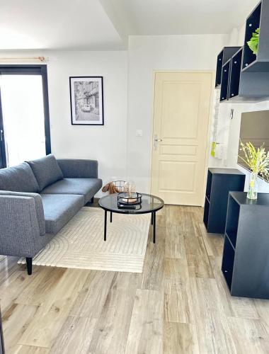 a living room with a couch and a table at Serenity, parking gratuit , 5 min Auxerre in Monéteau