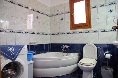 y baño con aseo, bañera y lavamanos. en Magdas house, en Centro histórico de Alónnisos