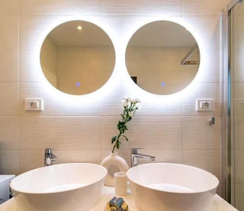 two sinks in a bathroom with two mirrors at Panorama Suite Dora with Jacuzzi in Palit