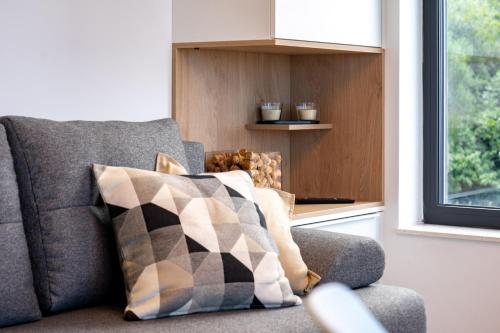 a gray couch with pillows sitting next to a window at Panorama Suite Dora with Jacuzzi in Palit