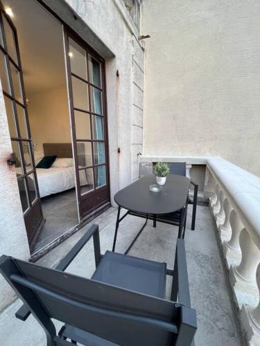 a balcony with a table and chairs and a bed at Appartement Élégant proche RER/ CDG / Parc des Expos in Sevran