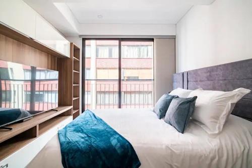 ボゴタにあるModern Loft in Downtown Bogotaの大きな白いベッドと青い枕のある寝室