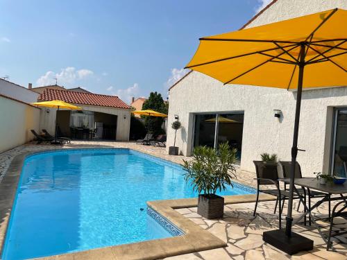 a swimming pool with a table and an umbrella at Les Pertuis Rochelais in Périgny