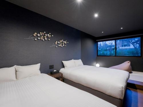 - 2 lits dans une chambre avec 2 fenêtres dans l'établissement Rakuten STAY VILLA Yatsugatake - 105 Stylish Design -, à Hokuto
