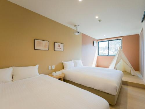 1 Schlafzimmer mit 2 Betten und einem Fenster in der Unterkunft Rakuten STAY VILLA Yatsugatake - 106 Family Room - in Hokuto
