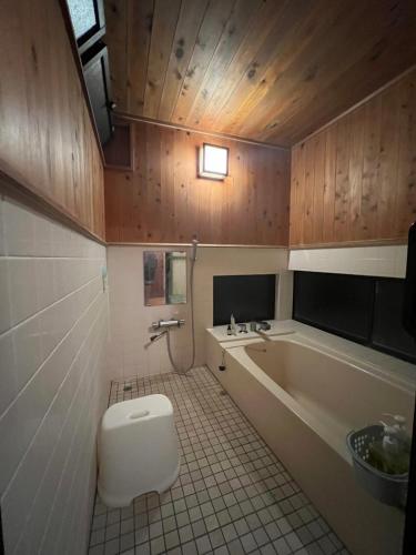 a bathroom with a tub and a toilet and a sink at Fukuro no Oyado Shinkan - Vacation STAY 59589v in Fuefuki