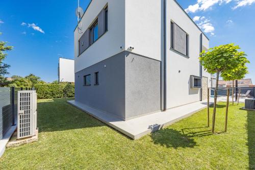 a white house with a tree in the yard at Villa Moon near the sea in Fažana