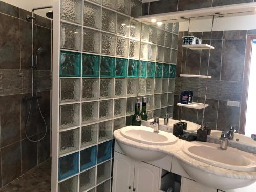 une salle de bain avec deux lavabos et une douche dans l'établissement Maison de village avec patio, à Bessan