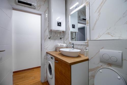 a bathroom with a sink and a washing machine at Apartments Euphoria East in Rijeka